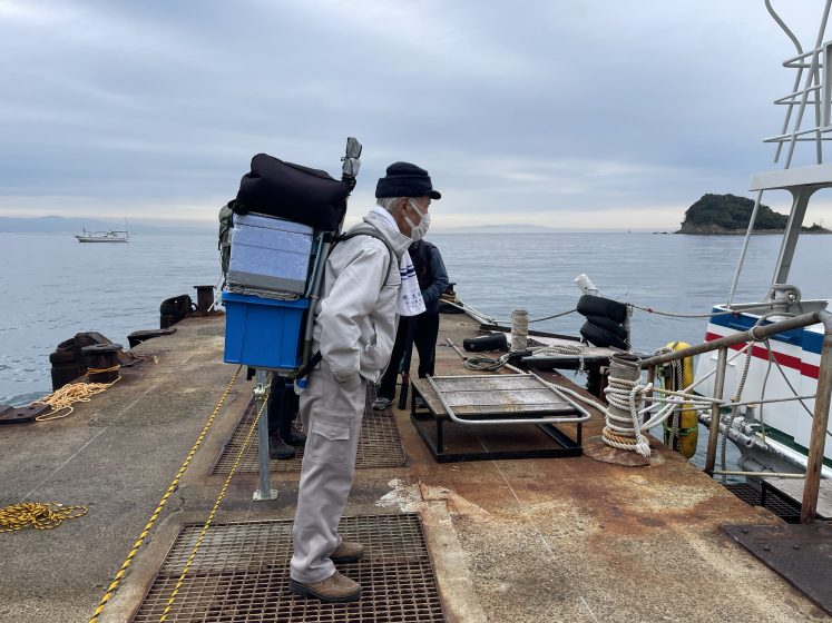 A person standing on a dock with a large container on their back